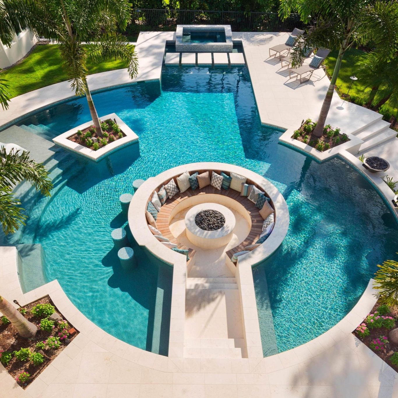Drone view of a luxury custom pool with built-in spa, by Jackson Pools, in a garden with a sunken lounge and several palm trees