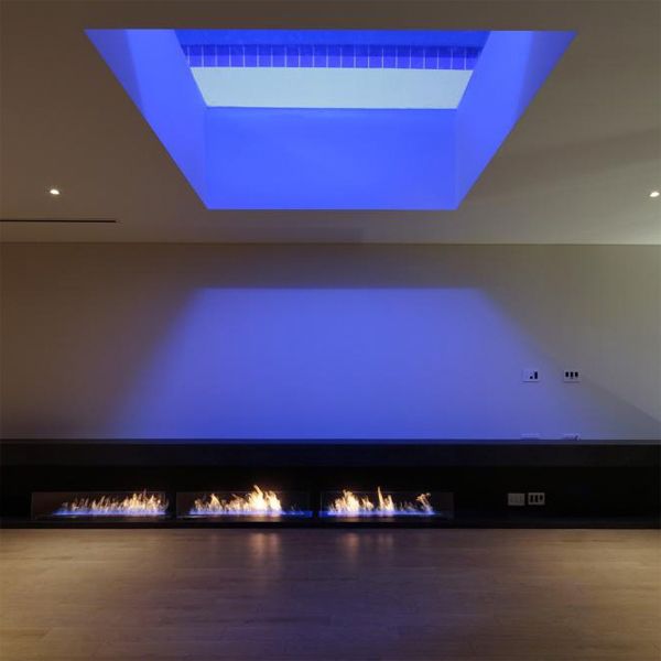 View of the living room of a modern design house with small fire pits, by Eastern Design Office, with a window in the roof, through which you can see the illuminated pool