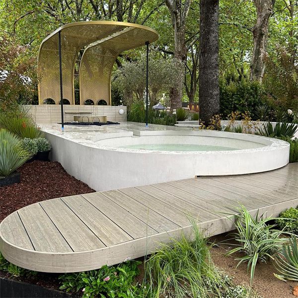 Custom white plunge pool with a modern and refined rounded design, by TLC Pools in a luxury garden with a golden pergola