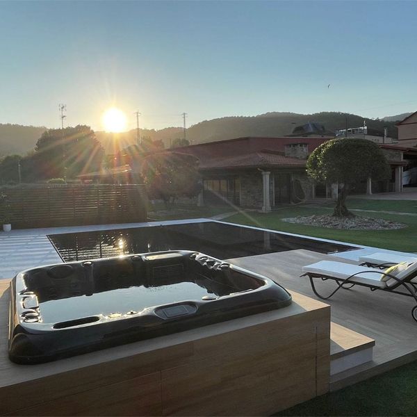 Overflow pool, mirror type, in a garden with different environments, including a wooden deck terrace with a spa, by Planetransparente, at sunset