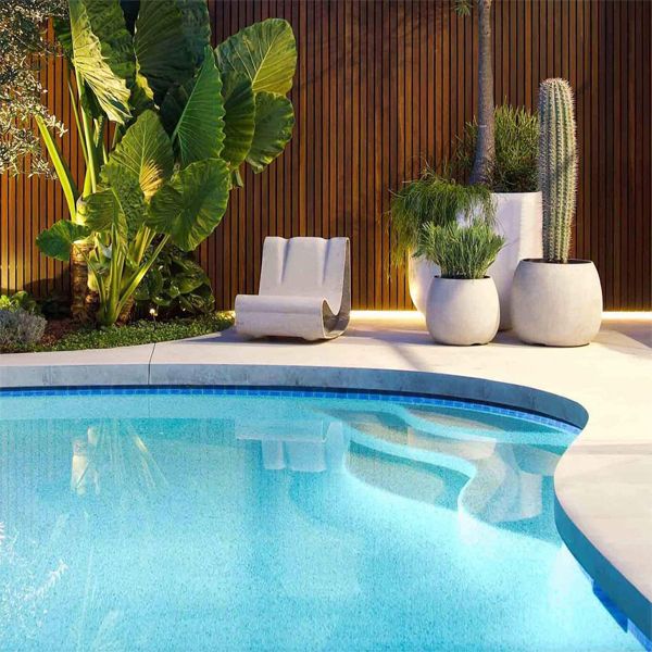 curved design pool, by Impressions Pools, lighted at night