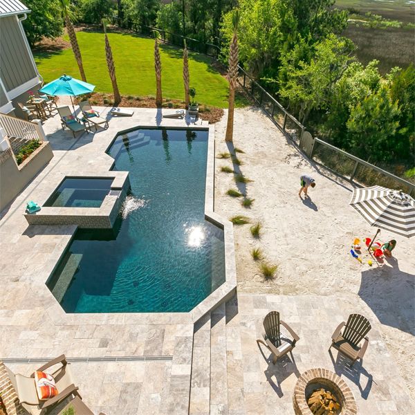 Drone view of a custom geometric pool, with built-in spa, in a large, modern garden with stone flooring and beach sand, by Aqua Blue Pools