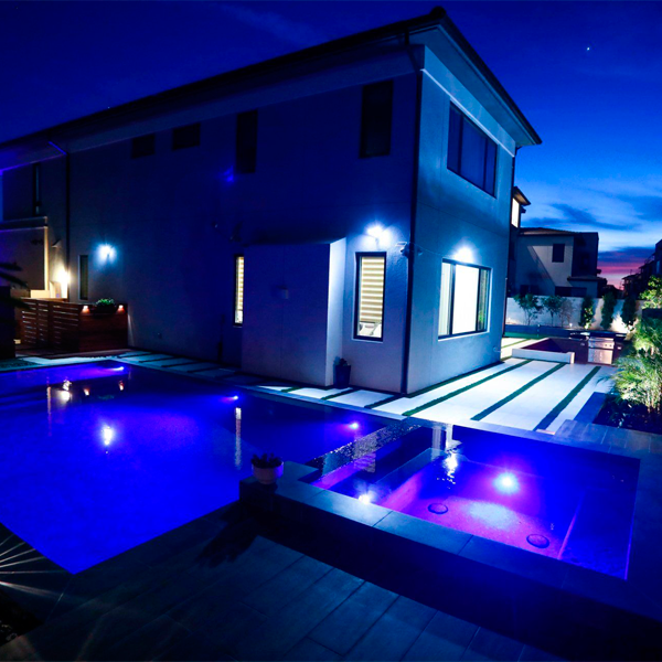 Conjunto piscina y spa negros con iluminacion nocturna