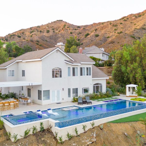 drone view of an infinity pool with built-in spa, in a landscaping project in a hill, by Green Scene Landscaping