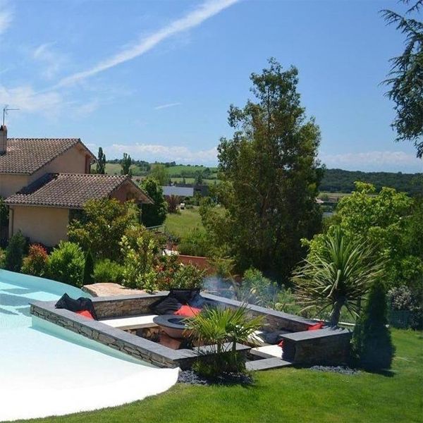 outdoor lounge by a beach-style infinity pool, in a private garden, by Piscines Iloé