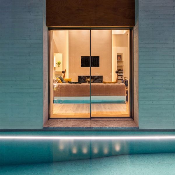 sitting room view from a minimalist modern pool at night, in a project by Divercity Architects