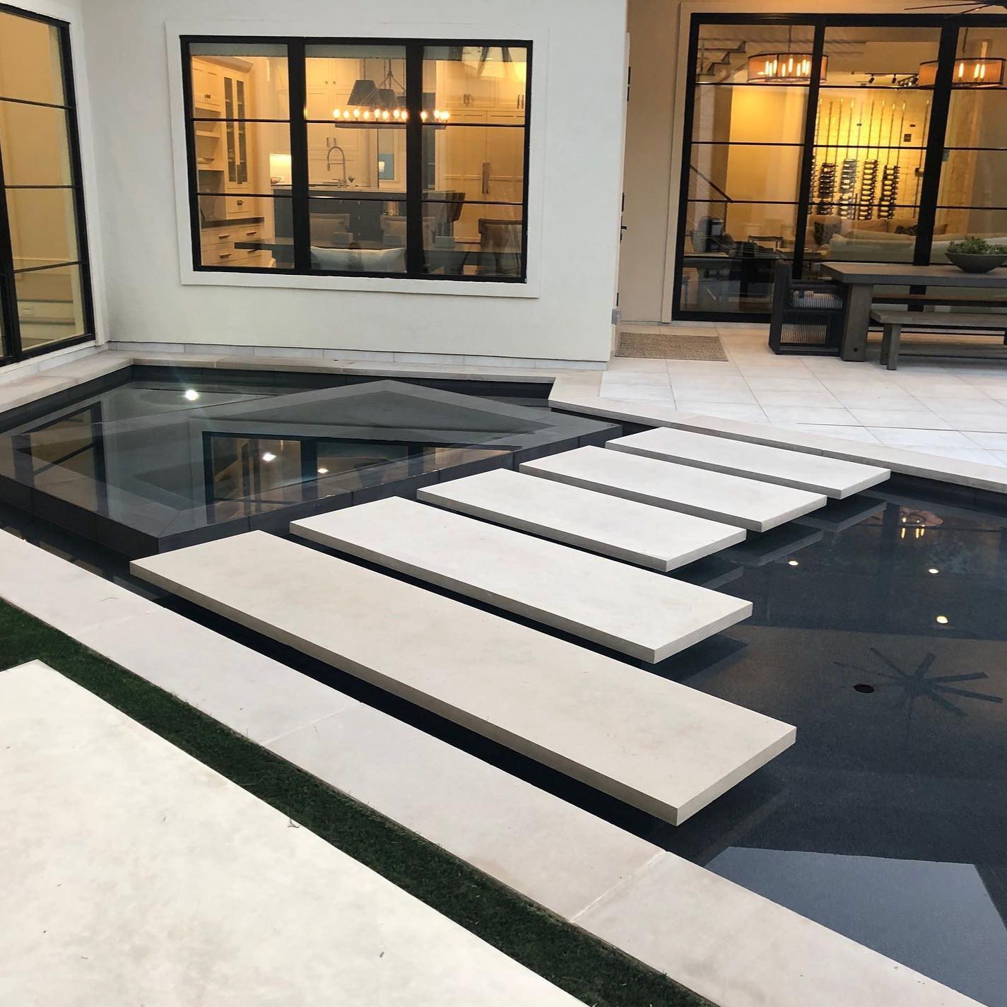 Floating separation steps between the spa area and the rest of an infinity pool, dark in color, by Pool Environments