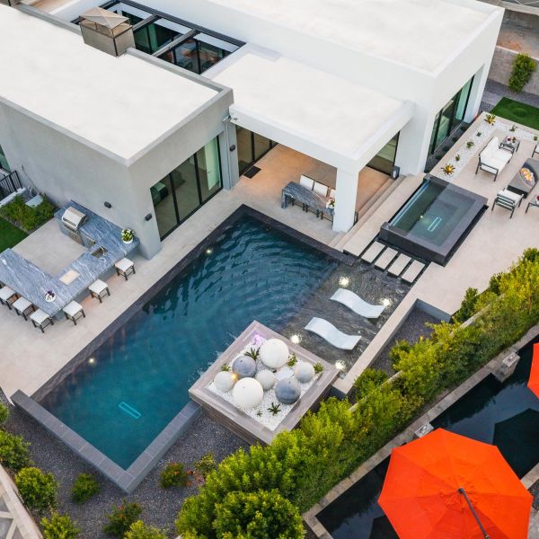 Drone view of a a modern and refined garden, with a geometric infinity pool, overflowing spa, outdoor lounge and relax area, by Lavender Landscape Design
