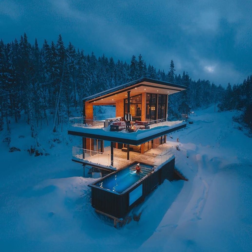 Vue dron at sunset of a mini container pool with a transparent underwater window, by Modpools, in a cabin in the middle of the snowy forest