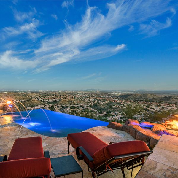 custom infinity pool, by Morris Pools, surrounded by natural stone and water features, at night