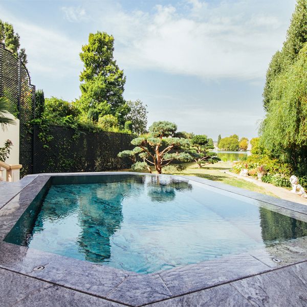 luxury steel overflow pool (mirror effect), with mobile bottom covered with marble, by Steel and Style in a house with a big garden and terrace