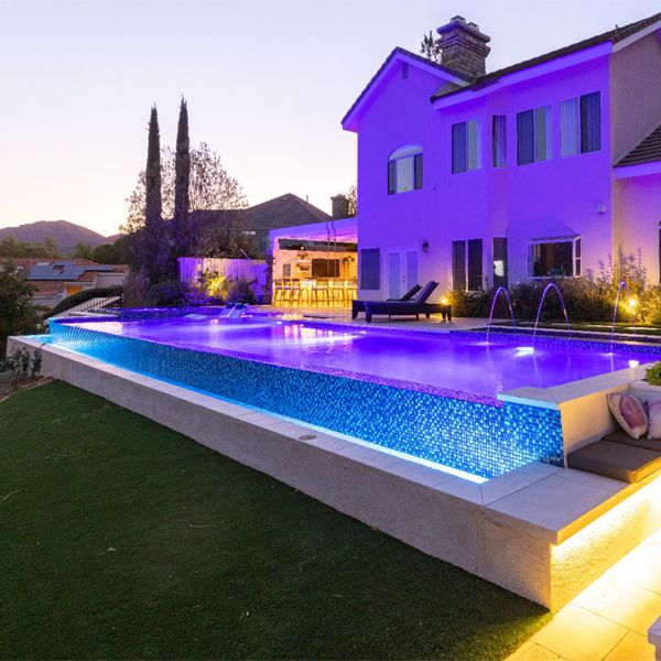 infinity pool with built-in spa, at sunset, in a landscaping project in a hill, by Green Scene Landscaping
