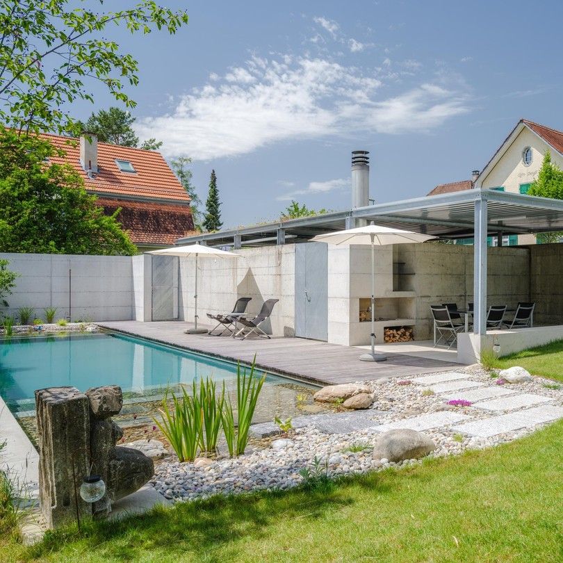 Traditional rectangular designed bio pool, in a modern and refined garden with wooden decking, by the Swiss company Stieger