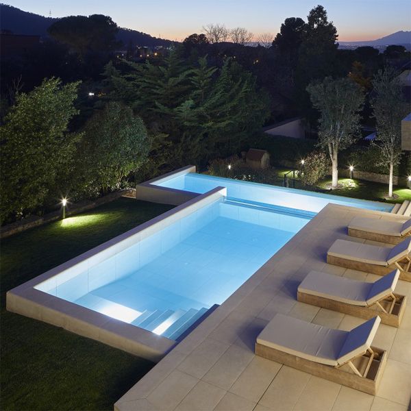 custom pool on two levels with a transparent wall at night in a project by GAAB Arquitectes