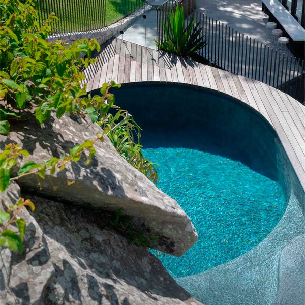 pool surrounded by wooden decking in a lush garden, by Secret Gardens