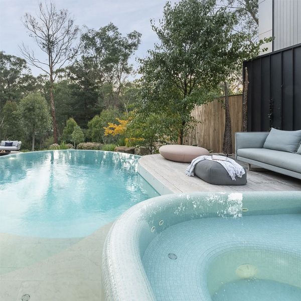 Overflowing infinity pool and spa by TLC Pools, in a modern garden with a wooden terrace.