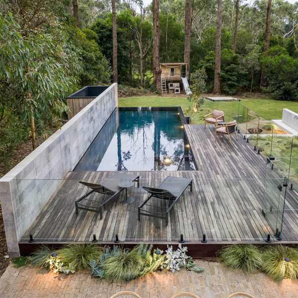 piscina elevada desbordante en tonos oscuros con exteriores en madera envejecida