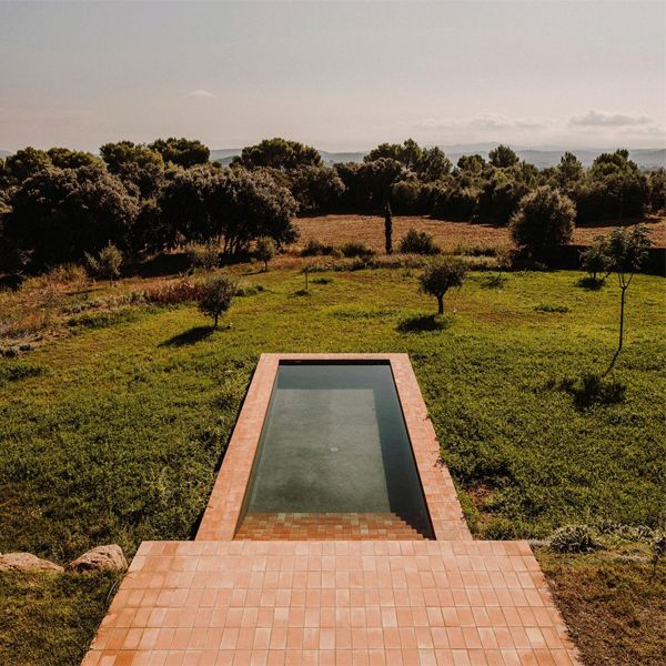 View of the Pool of Casa Ter, a project by Mesura in the countryside. A pool with a classic rectangular design in which brick takes center stage, both inside and outside