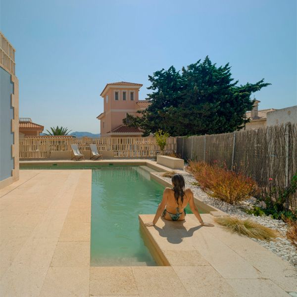 woman sitting on the edge of a l-shaped pool, in a proyect by Pepa Diaz Arquitecta