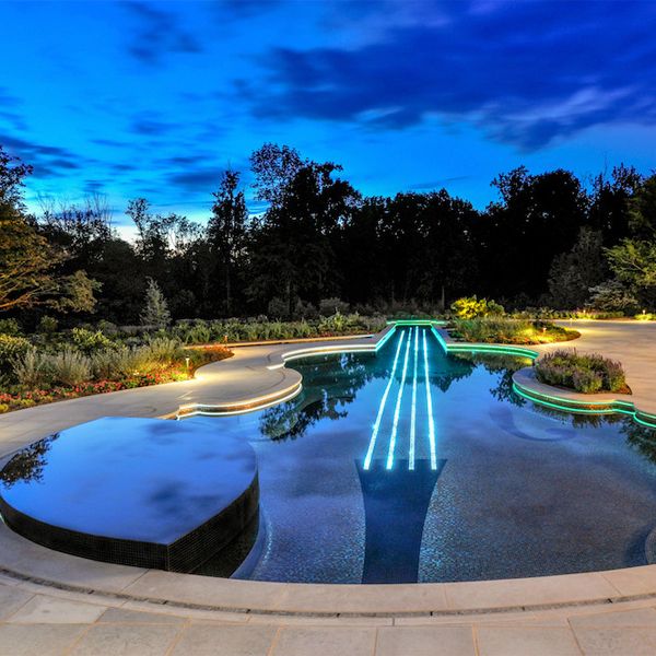 a unique pool and spa with a violin desin, at night, by Cipriano Landscape Design