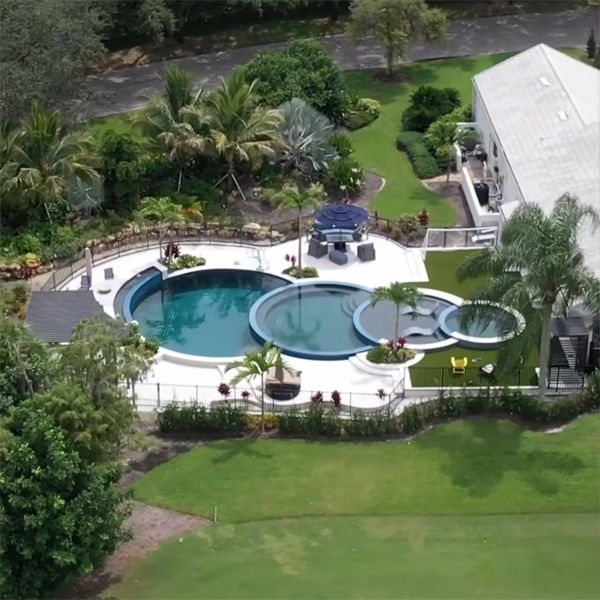 drone view of an infinity pool on 4 levels, in the shape of superimposed rings, by Lucas Lagoons, with a combo of pebbletec and glass mosaic as coating