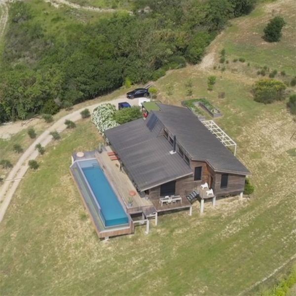 Drone view of an infinity lap pool in a house with a wooden terrace, in a project by Aloha Concepteur Exterieurs, in the mountain