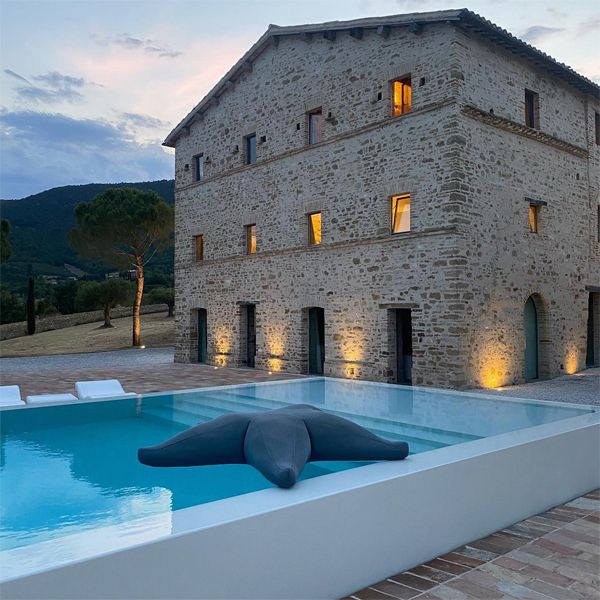 Infinity white pool, with a minimalist design, in a rustic space, in the middle of the countryside, from a project by Wespi, at sunset de Meuron Romeo Architetti, at sunset