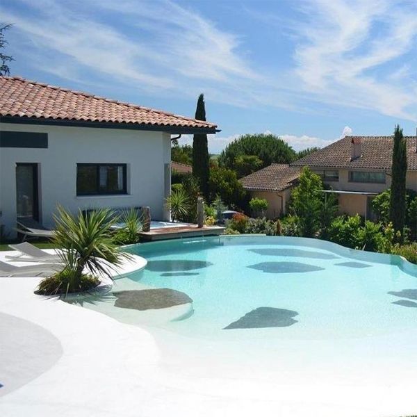 Beach-style infinity pool, in a private garden, by Piscines Iloé