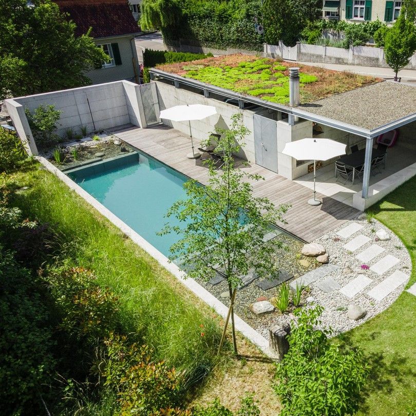 Drone view of a traditional rectangular designed bio pool, in a modern and refined garden with wooden decking, by the Swiss company Stieger