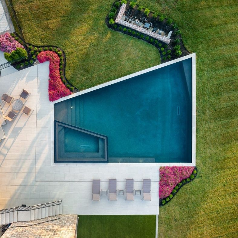 Drone view of a private pool with built-in spa, geometric trapezoidal designed, in a minimalist garden, by Basin Pool Designs