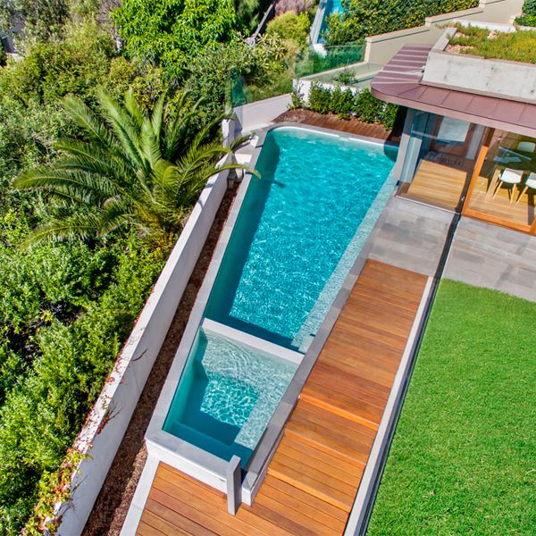 drone view of a custom private pool with a built-in spa, surrounded by wooden deck, in a project by Trademark Pools