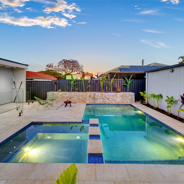 Private pool and built-in spa, by Mineral Pools, surrounded by stone pavement in a garden of a house in Manley (Sydney), lighted at sunset