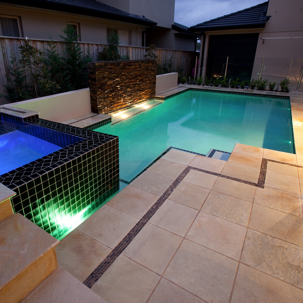 white swimming pool and black spa at night