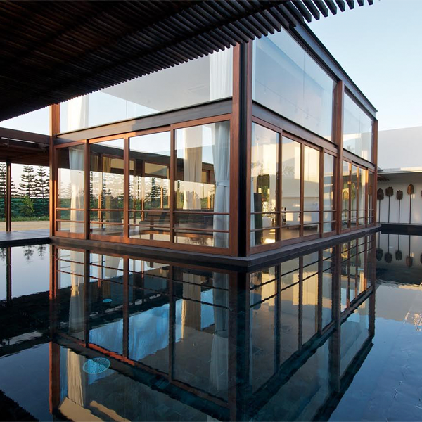 piscina rodeando vivienda acristalada