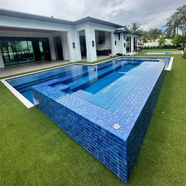 Spectacular effect achieved in this private custom pool, with an overflowing raised spa, bright tiles, by Chief Pools Plastering