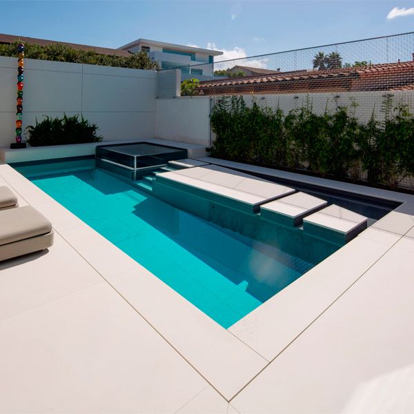 A unique custom built moving floor pool with see-through spa by Mission Pools in a small backyard