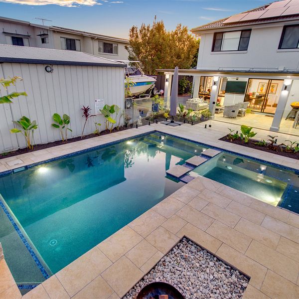 Private pool and built-in spa, by Mineral Pools, surrounded by stone pavement in a garden of a house in Manley (Sydney)