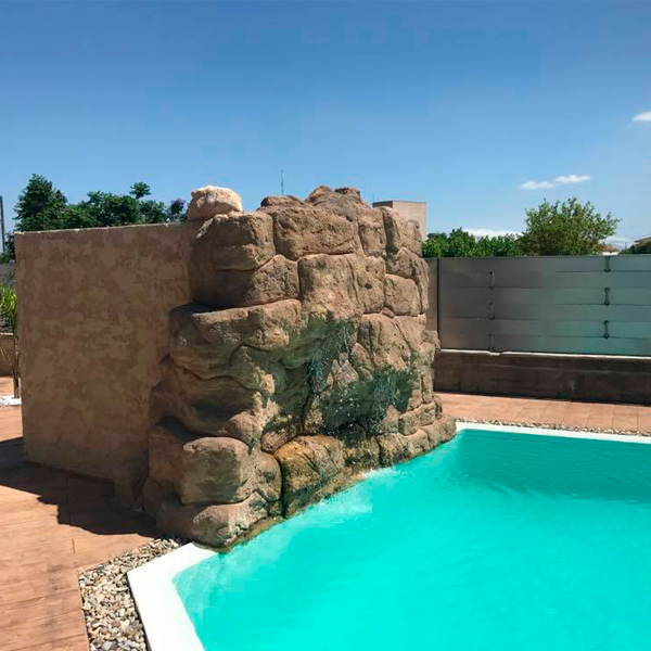 piscina desbordante de formas geométricas y decoración de piedras alrededor y cascada en imitación de piedra