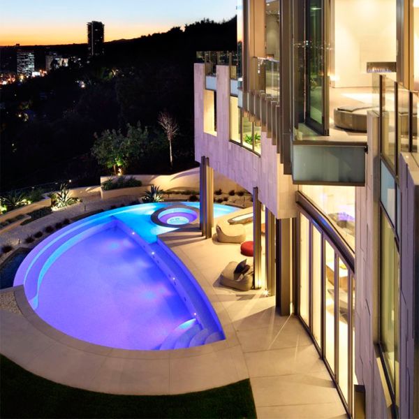 drone view of a custom infinity pool with built-in spa at night, in a project by Landry Design Group