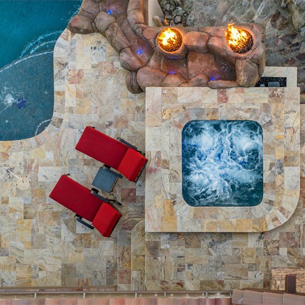 drone view of a custom spa and pool, by Morris Pools, surrounded by natural stone and water features