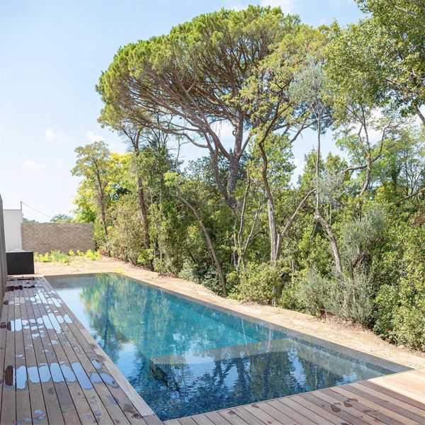 infinity lap pool by MCR Piscines and wooden decking in a side garden