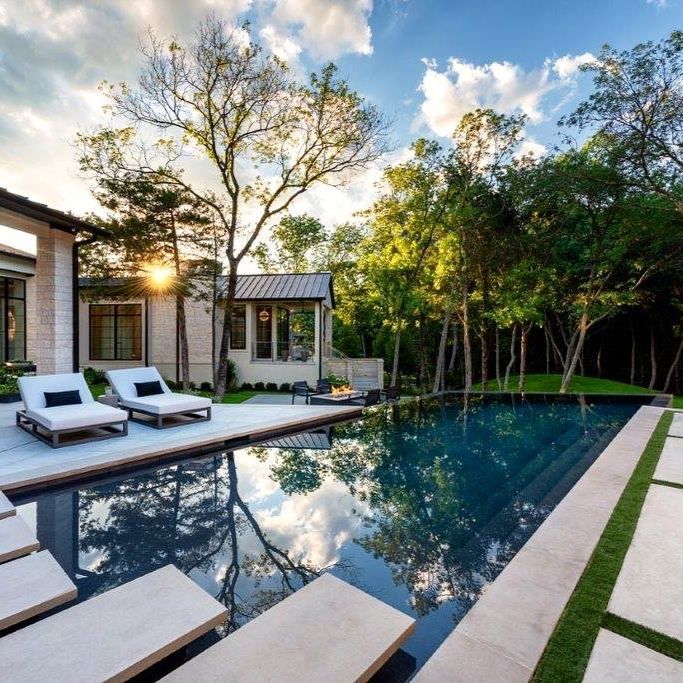 Design infinity pool in straight lines and angles, with a dark coating, by Pool Environments, with floating steps on the surface and a solarium area with sun loungers