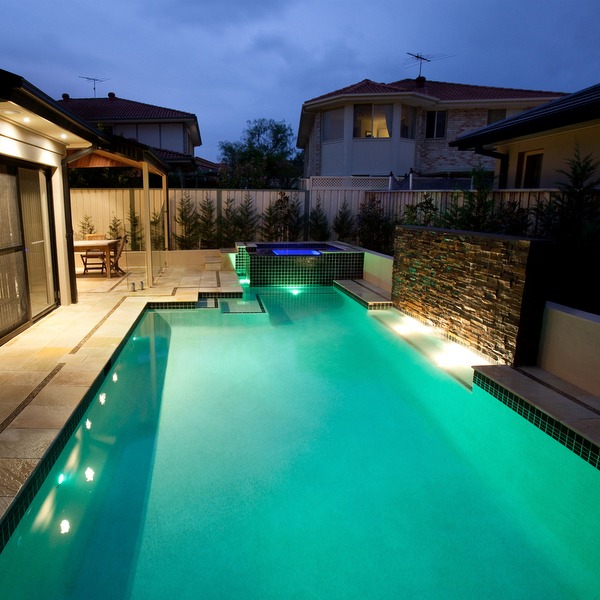 white swimming pool and black spa at night