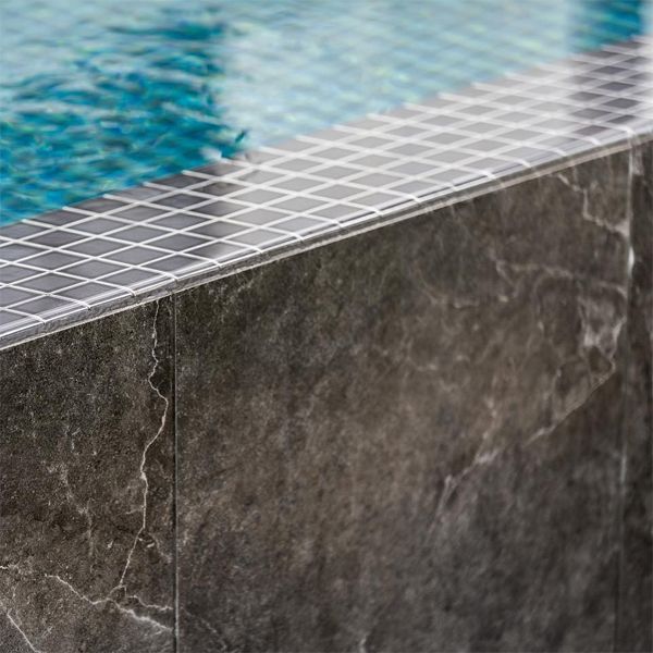 dark glass tile and natural stone in an infinity pool by Coastal Pools and Spas