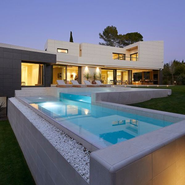 custom pool on two levels with a transparent wall at night, in a project by GAAB Arquitectes