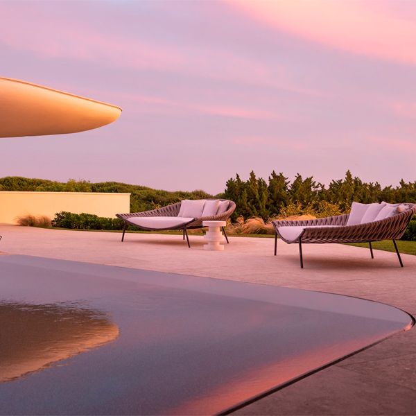 a unique and futuristic mirror pool design in a project by Rees Roberts, at sunset