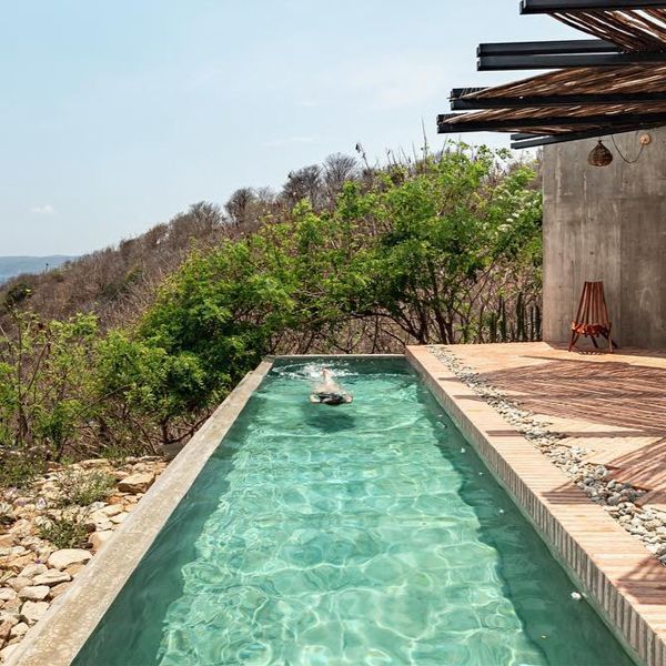 a woman swimming in an infinity pool of a rustic design house, in a project by Espacio 18 Arquitectura