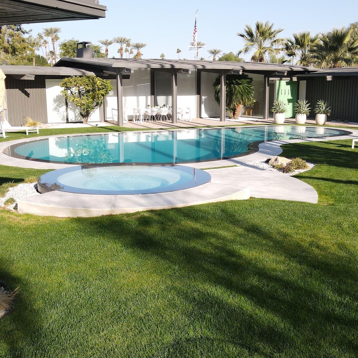 Beautiful overflow pool with kidney-shaped design and independent spa, by MPS Builders, with a contrast between the white interior coating and the dark color of the overflowing space, in a modern garden