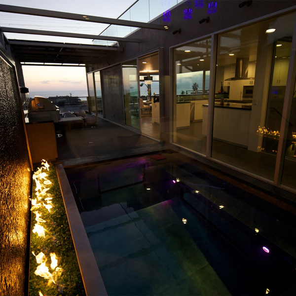 stainless steel mini pool with transparent windows, next to a fire space, in a project by David Hertz Architects FAIA, at sunset