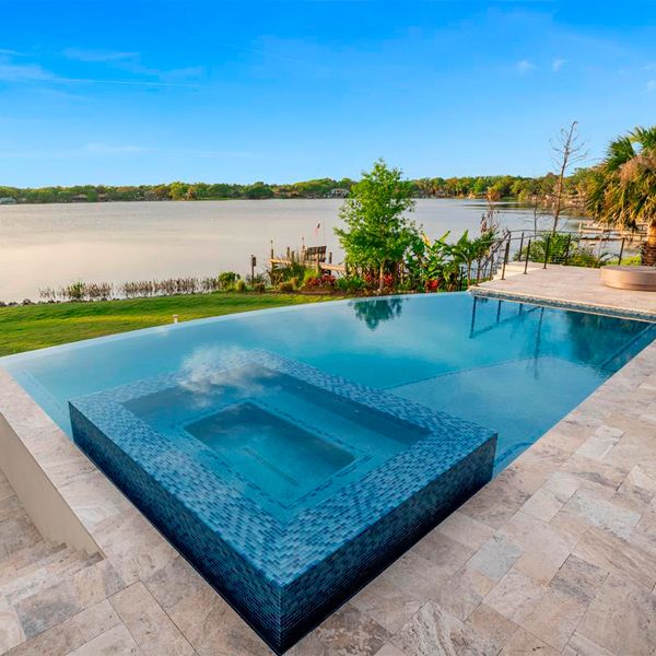 Custom infinity pool with built-in spa, by All Custom Pools, with lake views